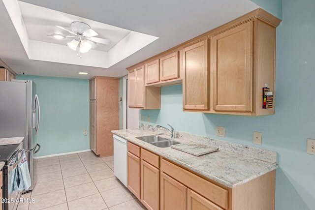kitchen featuring light brown cabinetry, appliances with stainless steel finishes, a sink, a raised ceiling, and a ceiling fan