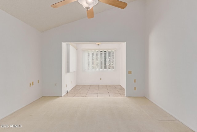 carpeted empty room with tile patterned floors, a ceiling fan, and lofted ceiling