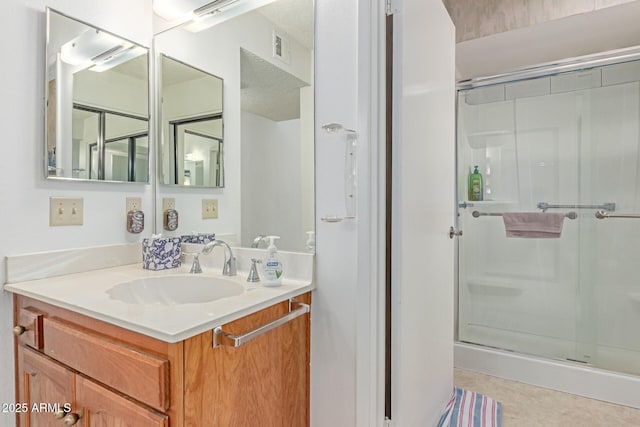 bathroom with visible vents, a shower stall, and vanity
