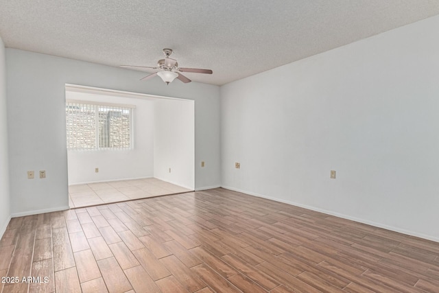 spare room with baseboards, a ceiling fan, a textured ceiling, and wood finished floors