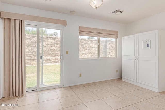 interior space with light tile patterned flooring, visible vents, multiple windows, and access to exterior