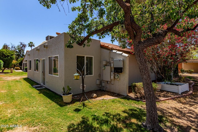 exterior space with a yard, a tile roof, and stucco siding