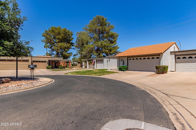 ranch-style house featuring a tiled roof, a garage, driveway, and stucco siding