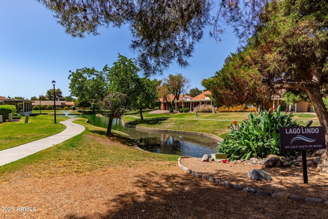 surrounding community with a water view and a yard