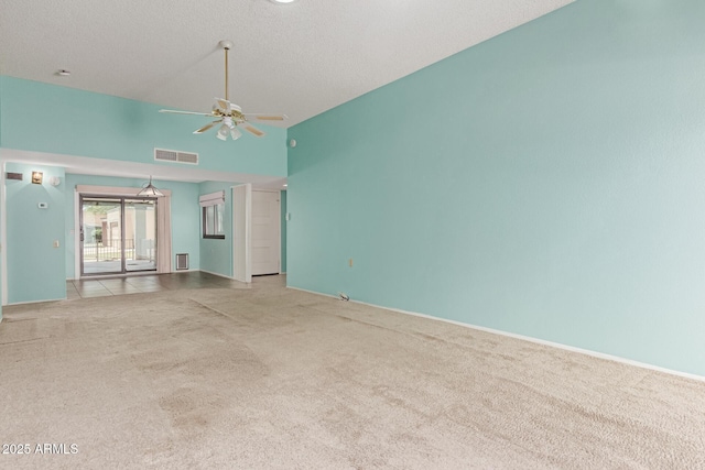 carpeted spare room with a ceiling fan, a textured ceiling, visible vents, and high vaulted ceiling