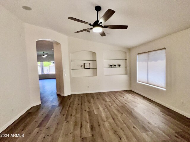 unfurnished living room featuring built in features, ceiling fan, hardwood / wood-style floors, and a textured ceiling