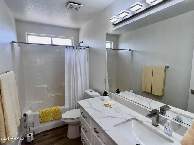 full bathroom featuring a textured ceiling, vanity, wood-type flooring, toilet, and shower / bath combo