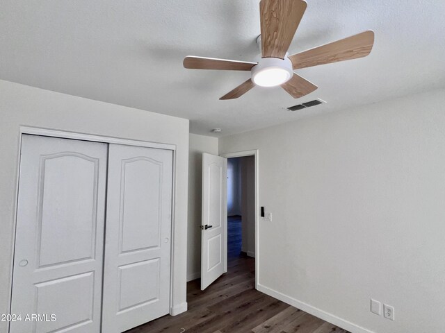 unfurnished bedroom featuring dark hardwood / wood-style floors, ceiling fan, and a closet