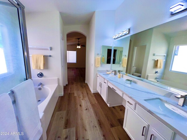 bathroom featuring toilet, hardwood / wood-style floors, vanity, ceiling fan, and a bathtub