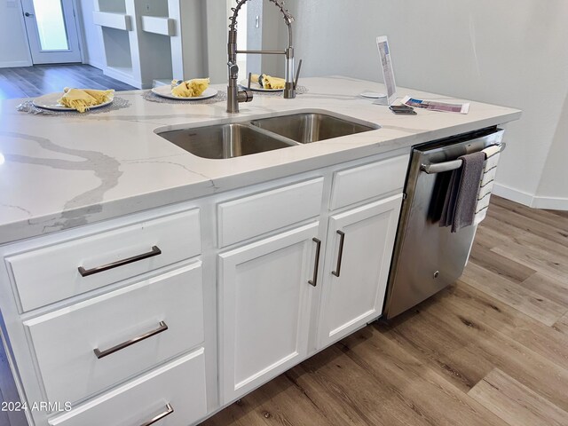 kitchen with dishwasher, light hardwood / wood-style floors, a healthy amount of sunlight, light stone counters, and white cabinets