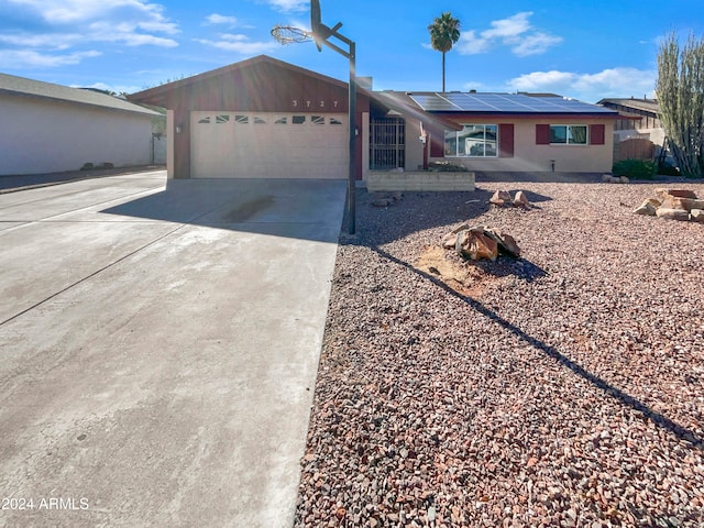 ranch-style house with a garage and solar panels