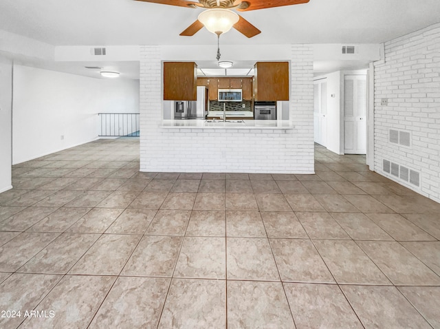 kitchen featuring appliances with stainless steel finishes, sink, tile patterned flooring, kitchen peninsula, and ceiling fan