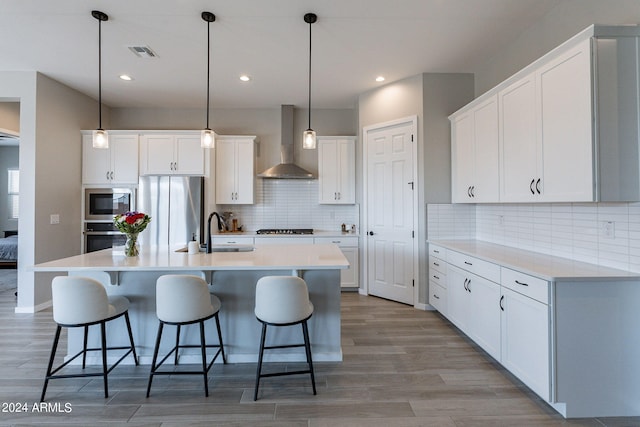 kitchen with light hardwood / wood-style flooring, sink, wall chimney range hood, and white cabinetry