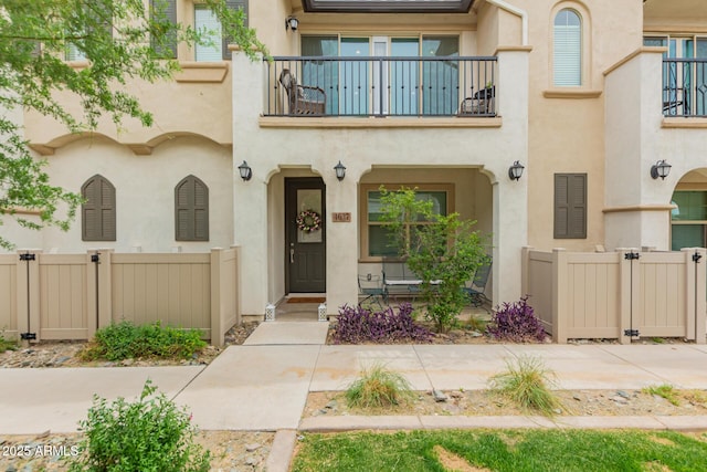 view of front of property with a balcony, fence, and stucco siding