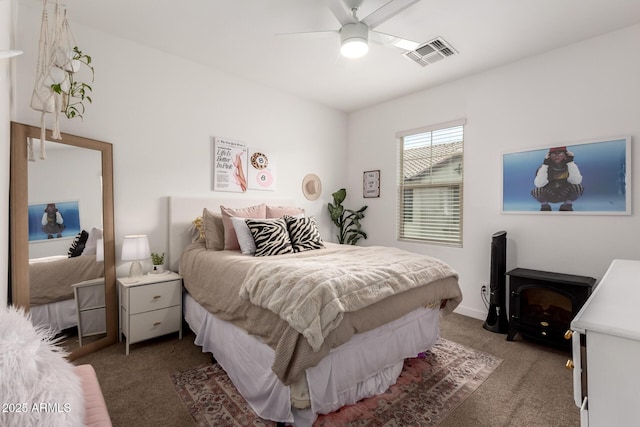 carpeted bedroom featuring ceiling fan and a wood stove