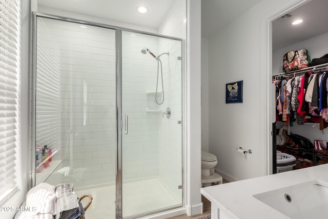 bathroom with a shower stall, toilet, recessed lighting, and a walk in closet