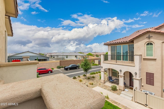 view of yard featuring a balcony, fence, and a residential view