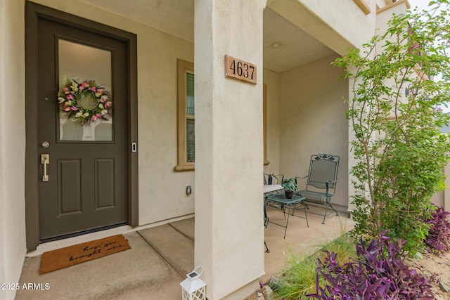 view of exterior entry featuring stucco siding and a porch