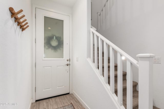 doorway to outside with light wood finished floors, stairs, and baseboards