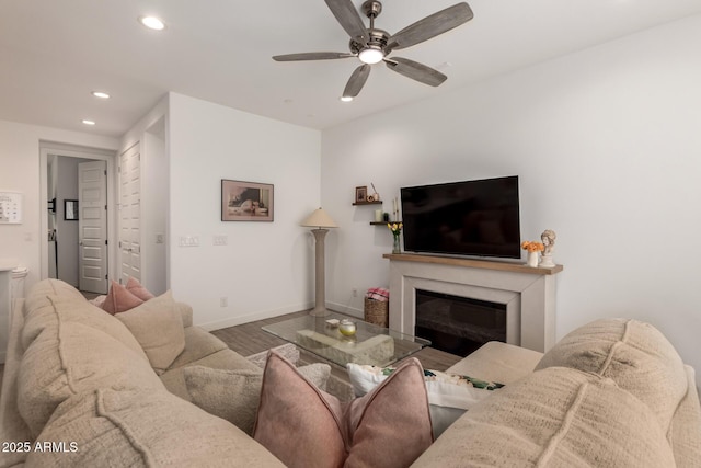 living room featuring wood finished floors, recessed lighting, ceiling fan, baseboards, and a glass covered fireplace