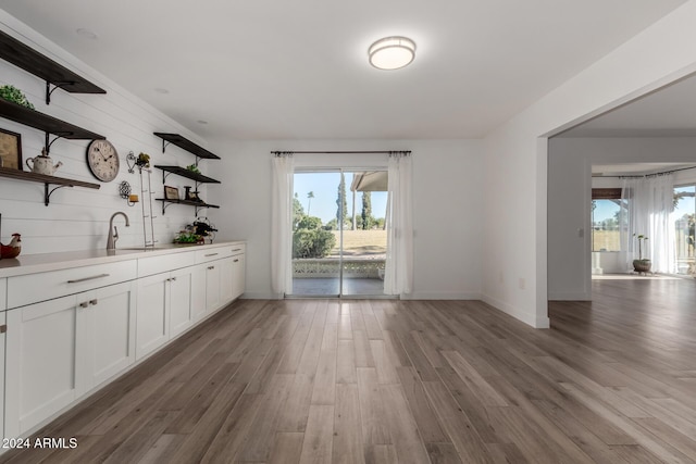 unfurnished dining area with wooden walls, light hardwood / wood-style flooring, and sink