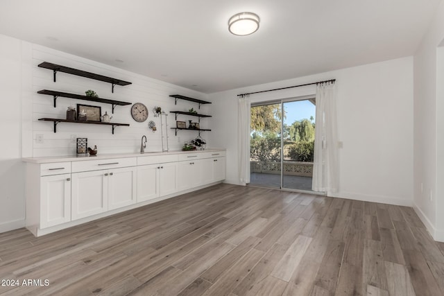 bar with white cabinets, light hardwood / wood-style flooring, and sink