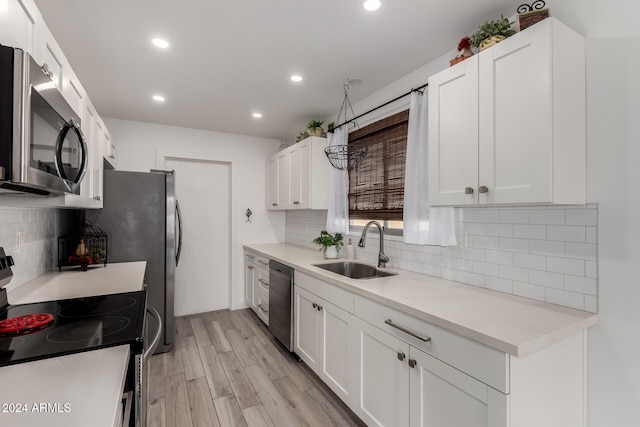 kitchen with sink, light hardwood / wood-style flooring, tasteful backsplash, white cabinetry, and stainless steel appliances