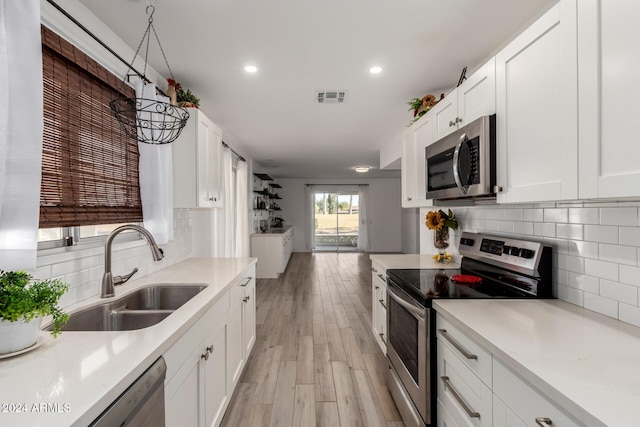 kitchen featuring sink, stainless steel appliances, white cabinetry, and light hardwood / wood-style flooring