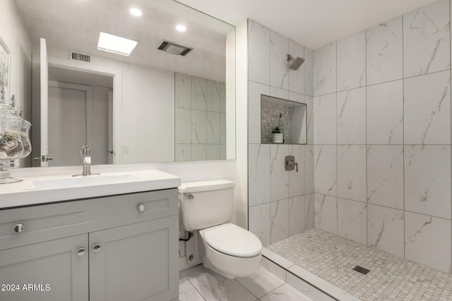 bathroom featuring toilet, a tile shower, vanity, and a skylight