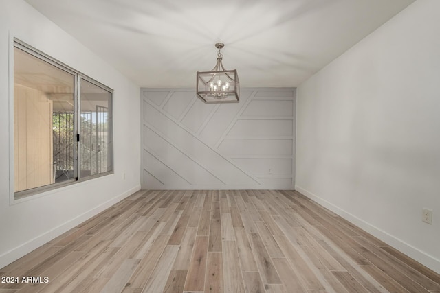 unfurnished dining area with a notable chandelier and light wood-type flooring