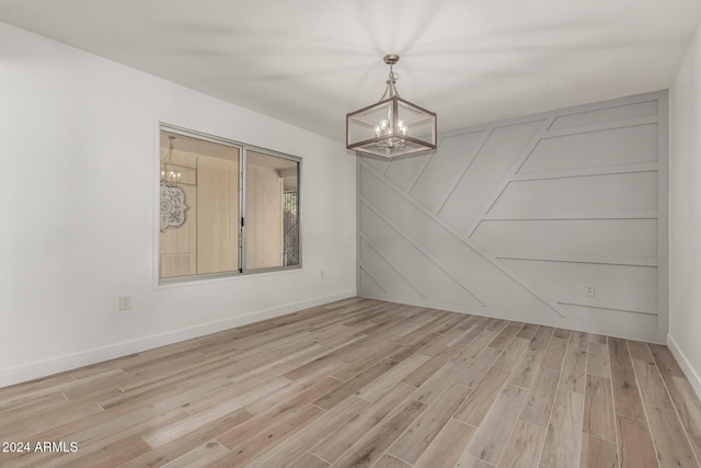 unfurnished room featuring a chandelier and light hardwood / wood-style flooring