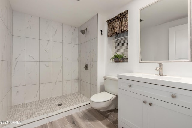 bathroom with tiled shower, vanity, and toilet