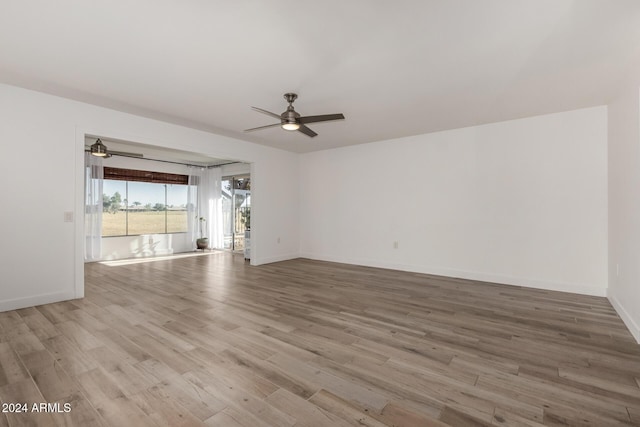 empty room with ceiling fan and light hardwood / wood-style flooring