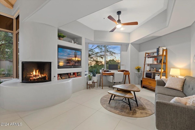 living room with built in shelves, ceiling fan, and light tile patterned floors