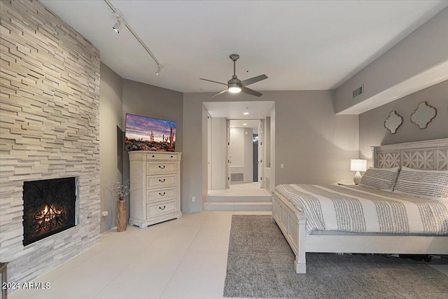 bedroom with ceiling fan, light tile patterned floors, track lighting, and a fireplace