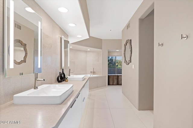 bathroom featuring tile patterned flooring, vanity, a relaxing tiled tub, and tile walls