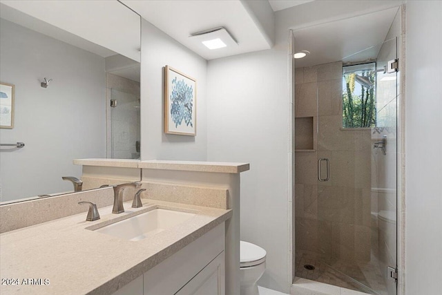 bathroom with toilet, a shower with door, and vanity