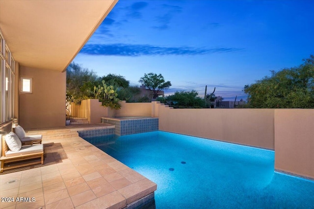 pool at dusk featuring a patio