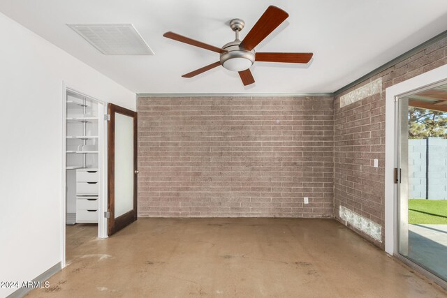 empty room with ceiling fan and brick wall
