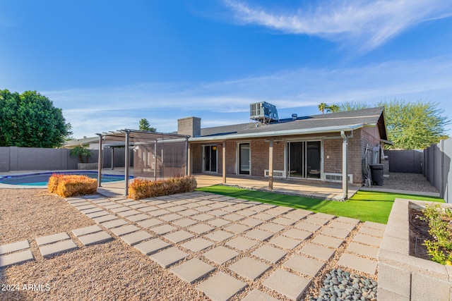 rear view of house featuring cooling unit, a fenced in pool, a pergola, and a patio