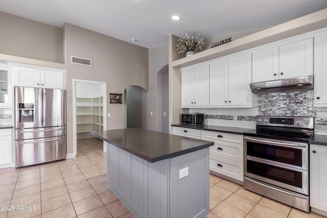 kitchen featuring white cabinets, a center island, light tile patterned flooring, and stainless steel appliances