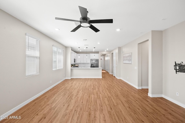 unfurnished living room with a ceiling fan, baseboards, recessed lighting, and light wood finished floors