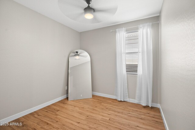 empty room with a ceiling fan, baseboards, and light wood-type flooring