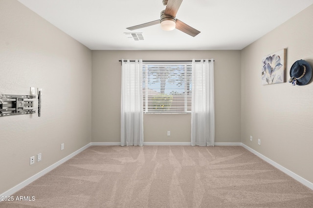 carpeted empty room featuring visible vents, a ceiling fan, and baseboards