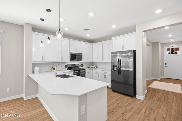 kitchen featuring a sink, light countertops, a peninsula, stainless steel appliances, and white cabinetry