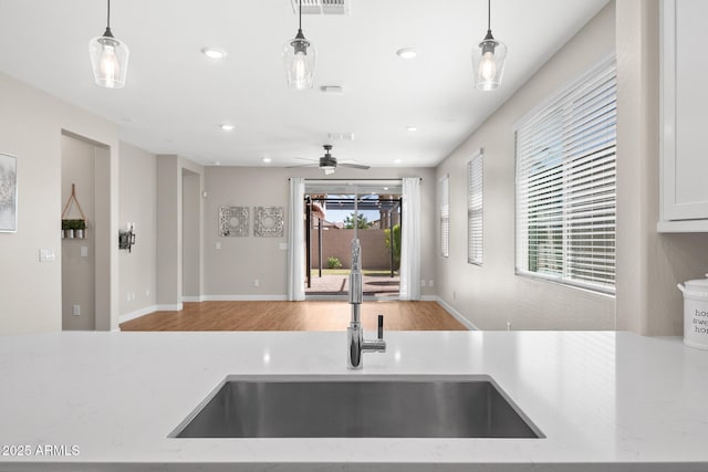 kitchen featuring a sink, a ceiling fan, pendant lighting, and wood finished floors