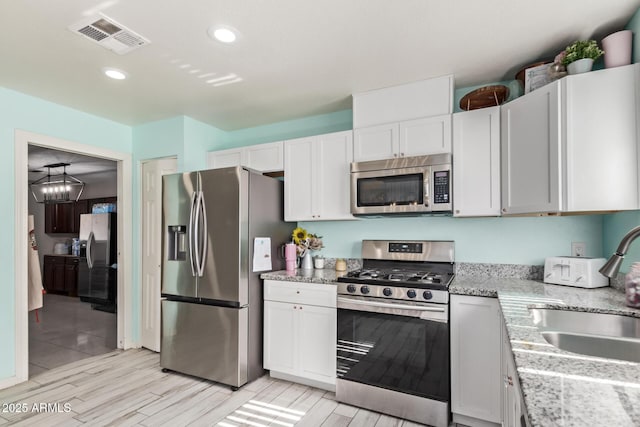 7357 W Cheryl Dr, Peoria, AZ 85345 - kitchen with visible vents, a sink, appliances with stainless steel finishes, white cabinetry, and light stone countertops