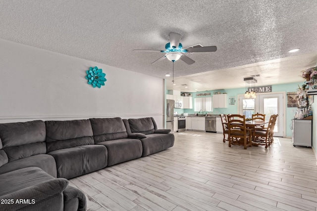 7357 W Cheryl Dr, Peoria, AZ 85345 - living room featuring light wood-style floors, a textured ceiling, and ceiling fan with notable chandelier