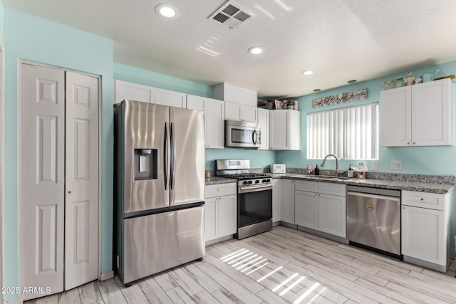 7357 W Cheryl Dr, Peoria, AZ 85345 - kitchen featuring wood finish floors, stone counters, visible vents, a sink, and stainless steel appliances