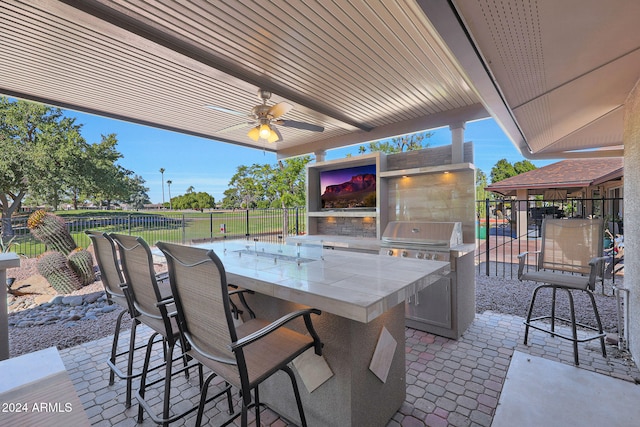 view of patio / terrace featuring an outdoor kitchen, ceiling fan, a grill, fence, and outdoor wet bar